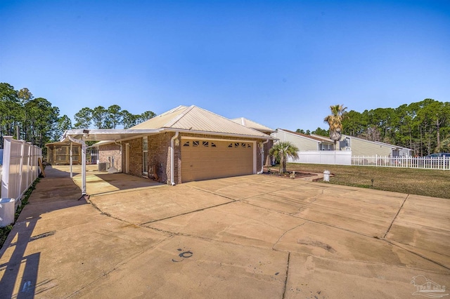 view of front facade featuring fence, metal roof, concrete driveway, and brick siding