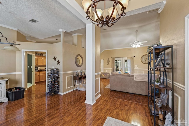 living area featuring visible vents, vaulted ceiling, dark wood finished floors, and ornamental molding