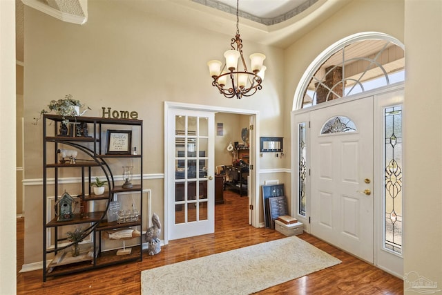 foyer entrance with a notable chandelier, a high ceiling, wood finished floors, and french doors