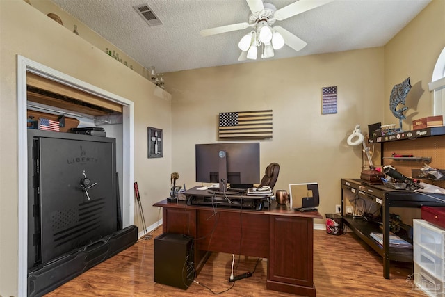 office space featuring a textured ceiling, wood finished floors, visible vents, baseboards, and a ceiling fan