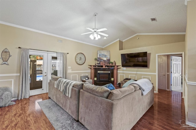 living area with french doors, a fireplace, visible vents, vaulted ceiling, and wood finished floors