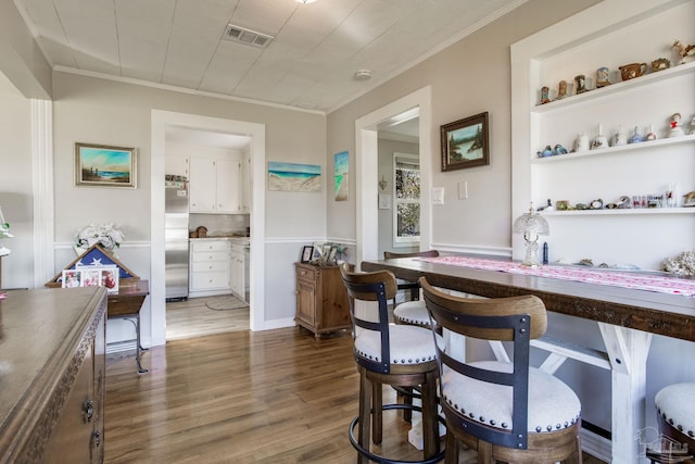 dining space with visible vents, dark wood finished floors, and ornamental molding