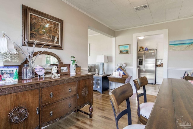 office area with light wood-style flooring, visible vents, and ornamental molding