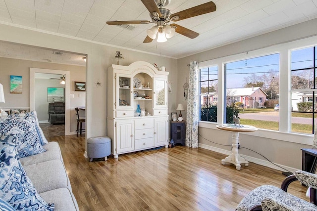 interior space featuring light wood-style floors, baseboards, ornamental molding, and ceiling fan