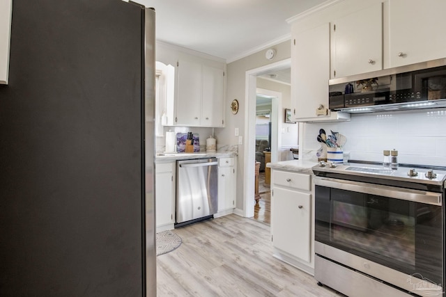 kitchen featuring white cabinets, decorative backsplash, stainless steel appliances, crown molding, and light countertops