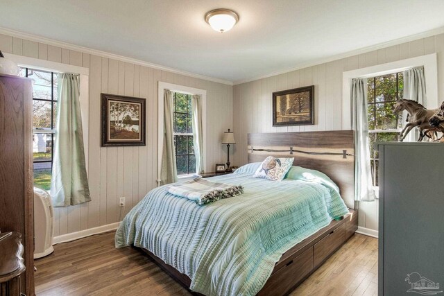 bedroom with baseboards, wood finished floors, and crown molding