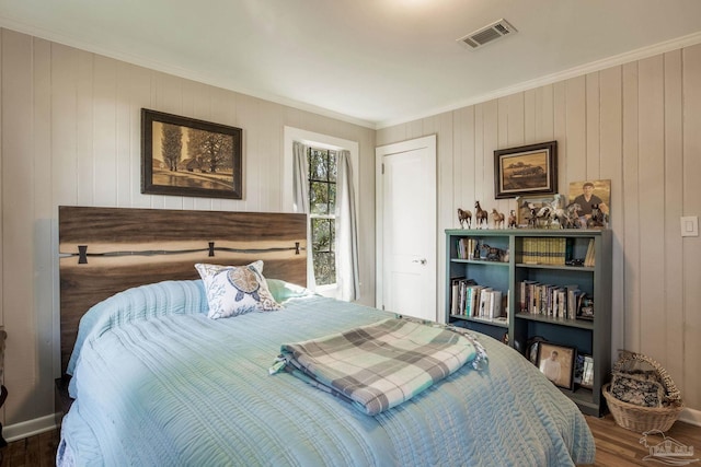 bedroom featuring ornamental molding, wood finished floors, visible vents, and baseboards