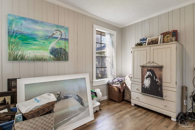 interior space featuring ornamental molding, wood-type flooring, and a textured ceiling