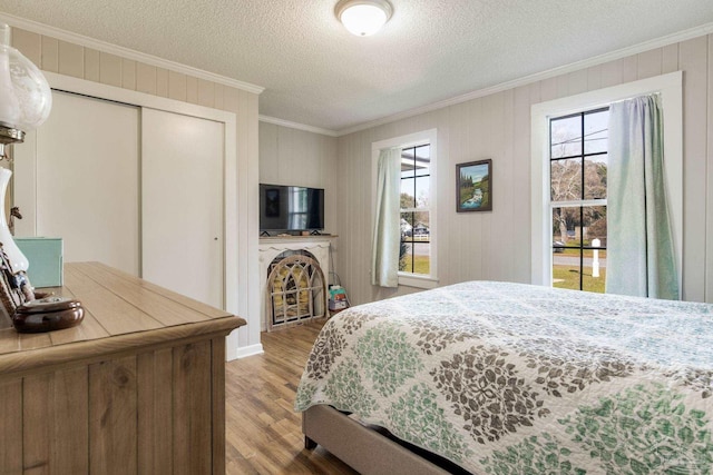 bedroom featuring light wood-style floors, multiple windows, and crown molding