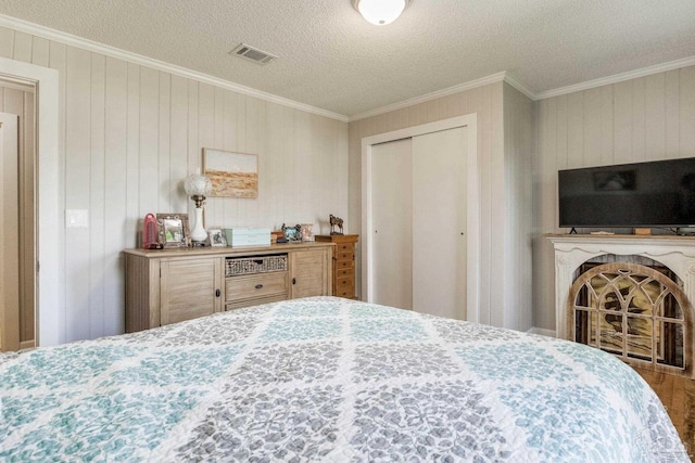 bedroom featuring a closet, visible vents, crown molding, and a textured ceiling