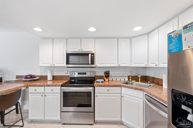 kitchen featuring light tile patterned floors, white cabinetry, sink, and stainless steel appliances