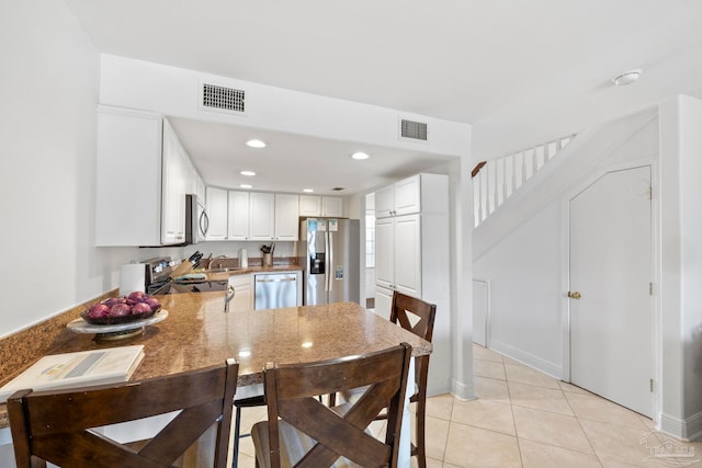 kitchen featuring appliances with stainless steel finishes, kitchen peninsula, white cabinetry, and light tile patterned floors