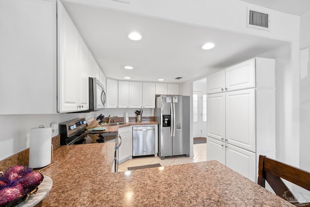 kitchen with stainless steel appliances, light tile patterned floors, kitchen peninsula, and white cabinetry