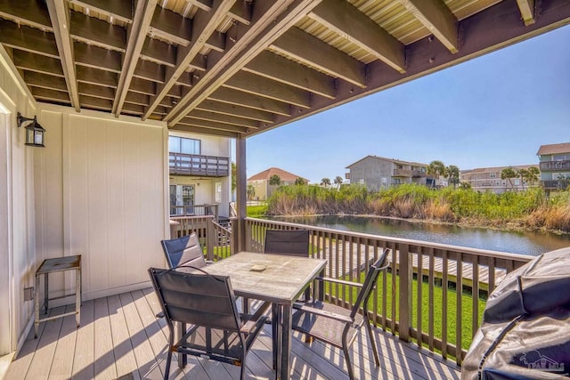 deck featuring a grill, a lawn, and a water view