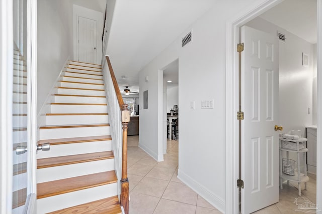 staircase featuring ceiling fan and tile patterned flooring