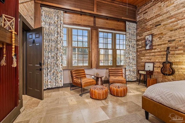 bedroom featuring brick wall and baseboards