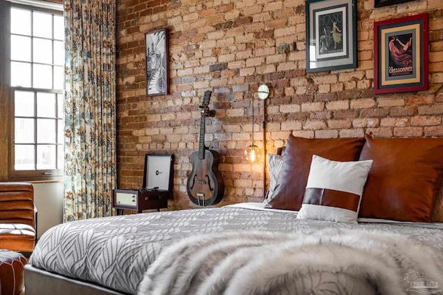 bedroom with multiple windows and brick wall