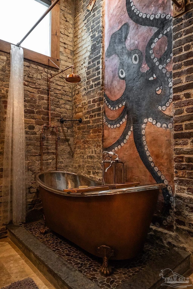 bathroom with a freestanding tub and brick wall