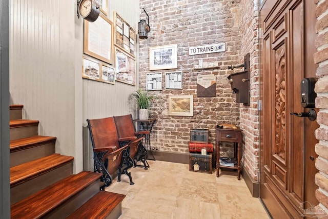 sitting room featuring brick wall and stairway