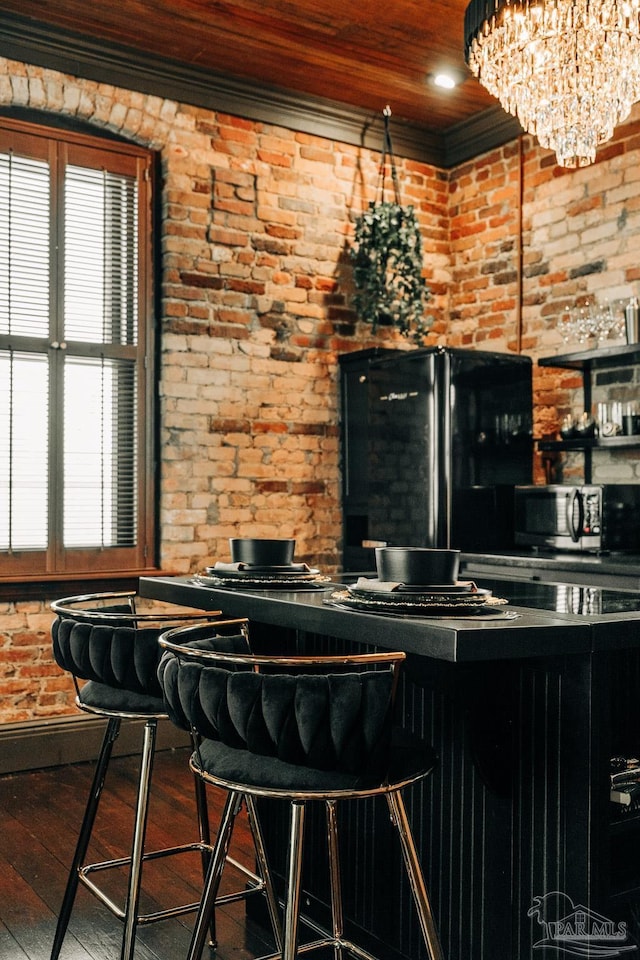 bar featuring wooden ceiling, hardwood / wood-style flooring, brick wall, stainless steel microwave, and freestanding refrigerator