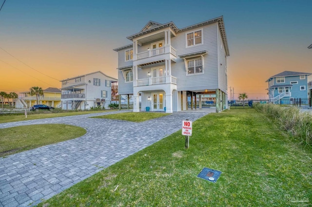 712 Maldonado Dr, Pensacola Beach, FL 32561 - coastal inspired home with a balcony, a carport, a front lawn, french doors, and decorative driveway