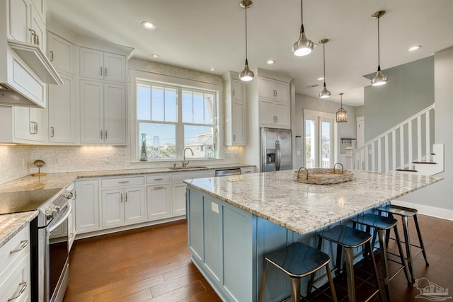 712 Maldonado Dr, Pensacola Beach, FL 32561 - kitchen featuring stainless steel appliances, a kitchen bar, dark wood-type flooring, and white cabinetry