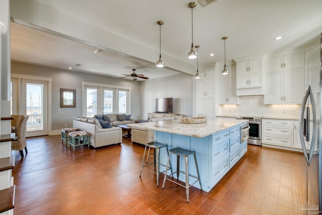 712 Maldonado Dr, Pensacola Beach, FL 32561 - kitchen with a kitchen bar, backsplash, dark wood-style floors, stainless steel appliances, and white cabinets