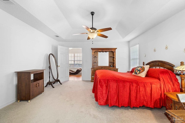 carpeted bedroom with a tray ceiling and ceiling fan