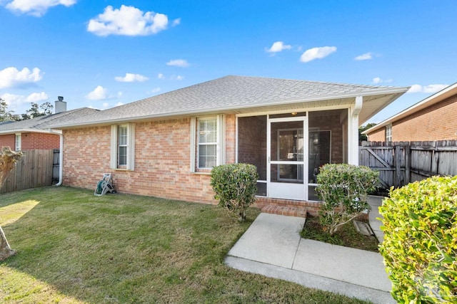 rear view of house with a yard and a sunroom