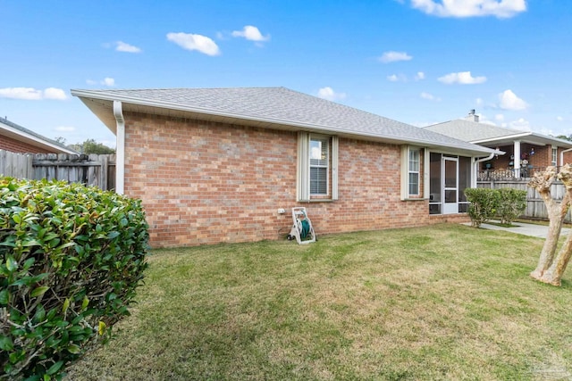 back of property with a lawn and a sunroom