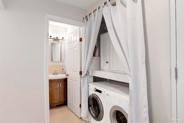 laundry room featuring sink, cabinets, a textured ceiling, washer and clothes dryer, and light tile patterned floors