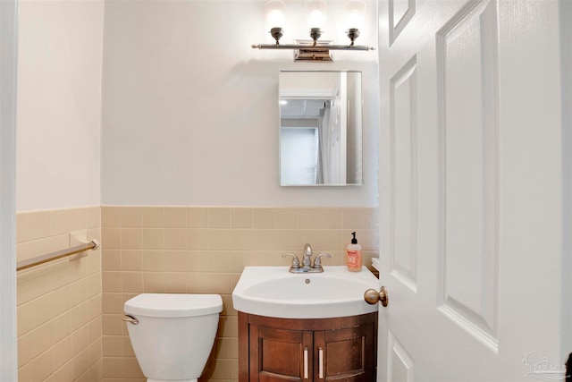 bathroom featuring vanity, tile walls, and toilet