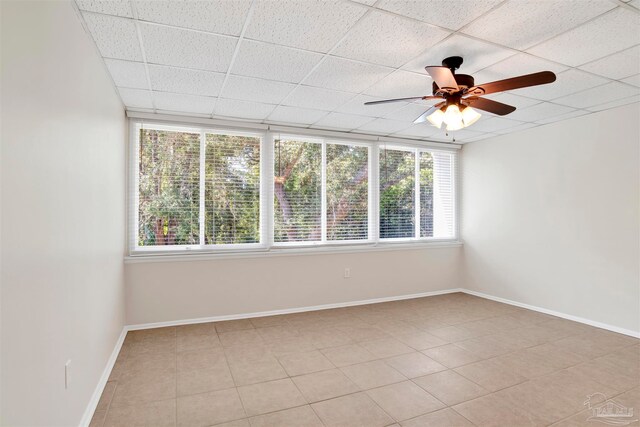 tiled spare room featuring ceiling fan and a drop ceiling