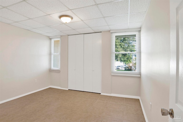 unfurnished bedroom with light tile patterned floors, a paneled ceiling, and a closet