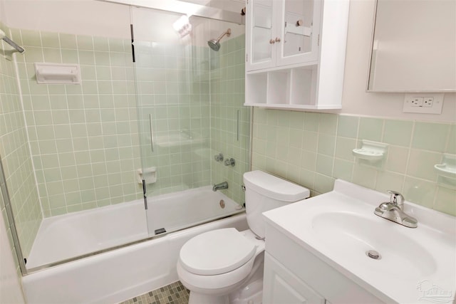 full bathroom featuring shower / bath combination with glass door, vanity, toilet, and tile walls