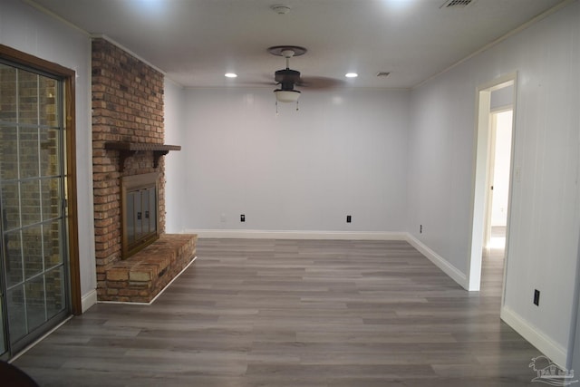 unfurnished living room with ornamental molding, wood finished floors, a fireplace, baseboards, and a ceiling fan
