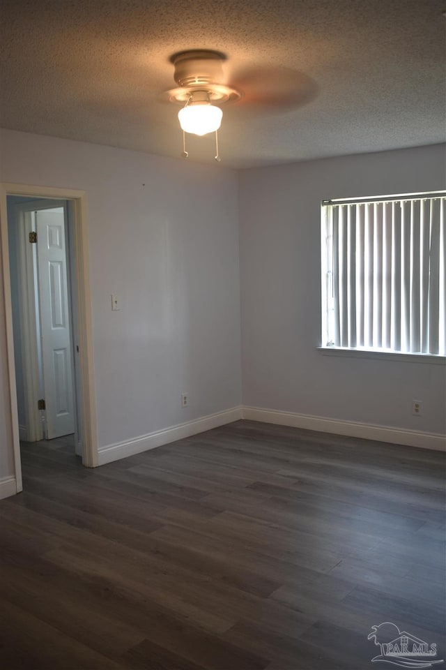 spare room with baseboards, ceiling fan, dark wood-style flooring, and a textured ceiling