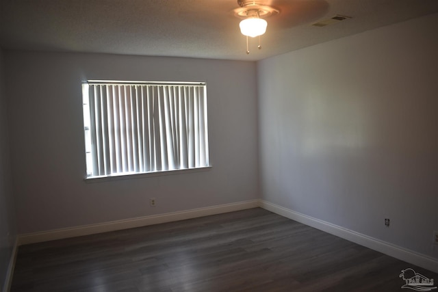 empty room with baseboards, ceiling fan, dark wood-style flooring, and visible vents