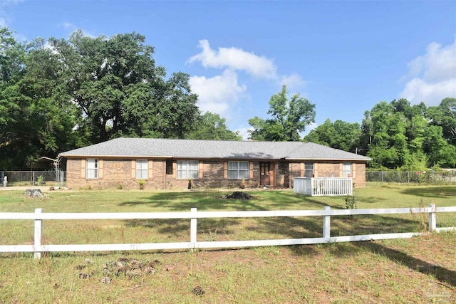 ranch-style home featuring brick siding, a front lawn, and a fenced front yard