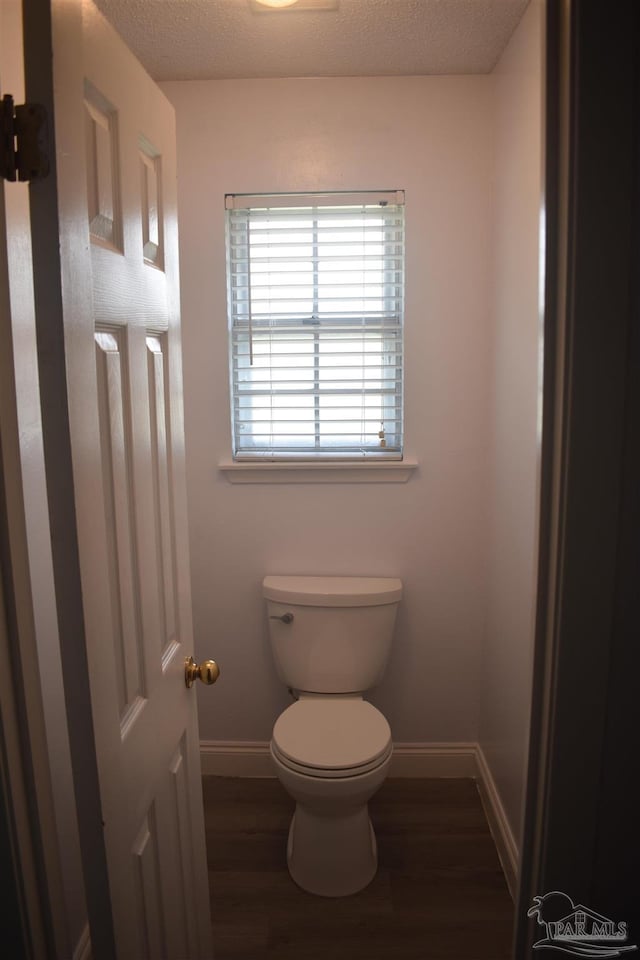 bathroom with baseboards, wood finished floors, and toilet