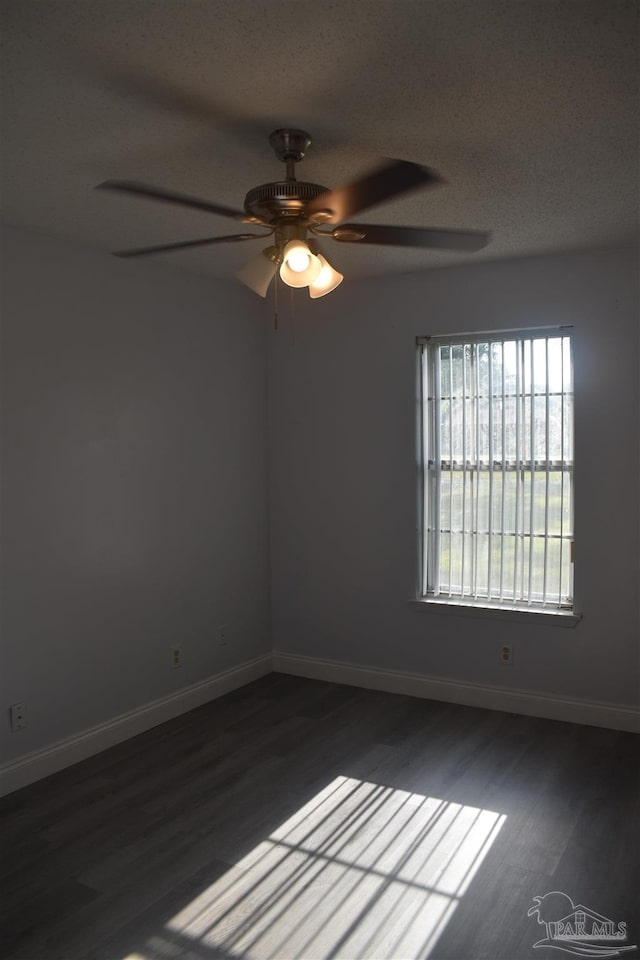 spare room with baseboards, a ceiling fan, and dark wood finished floors