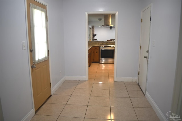 hall with baseboards, a healthy amount of sunlight, and light tile patterned floors