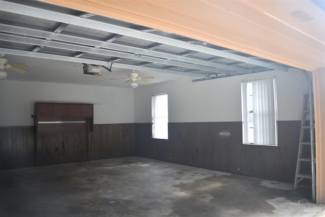 garage with a garage door opener, wainscoting, and wood walls