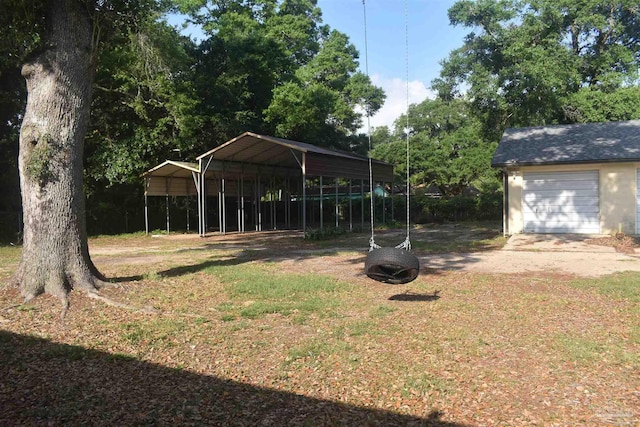 view of yard featuring a garage, a detached carport, and driveway