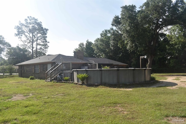 back of property with a lawn, an outdoor pool, stairs, and a chimney