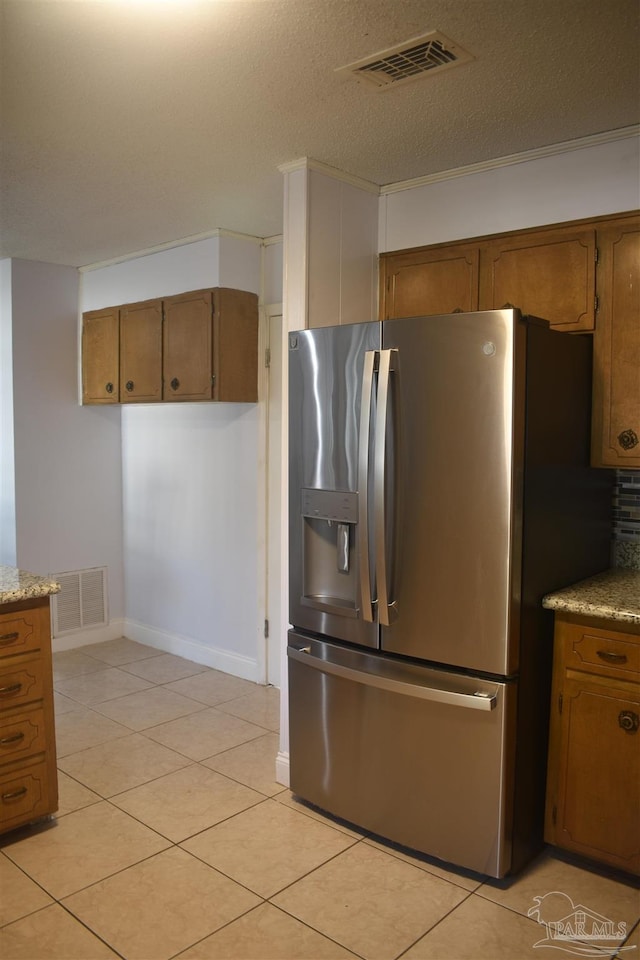 kitchen featuring brown cabinets, stainless steel refrigerator with ice dispenser, and visible vents
