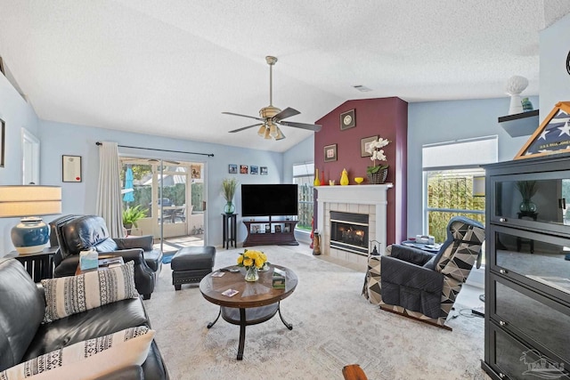 living room featuring ceiling fan, vaulted ceiling, a fireplace, a textured ceiling, and light carpet