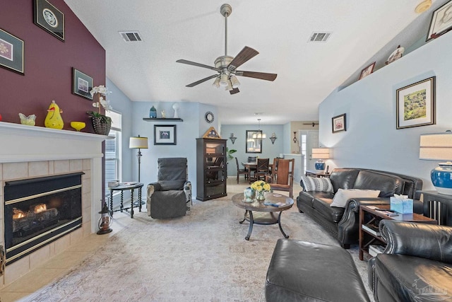 living room featuring ceiling fan, plenty of natural light, a textured ceiling, and a fireplace