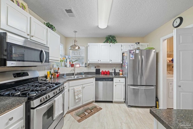 kitchen with washer / clothes dryer, white cabinetry, stainless steel appliances, decorative backsplash, and sink