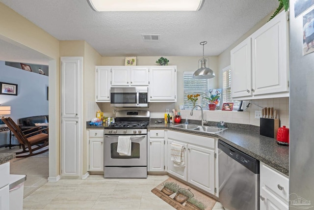 kitchen featuring a textured ceiling, appliances with stainless steel finishes, white cabinetry, and sink